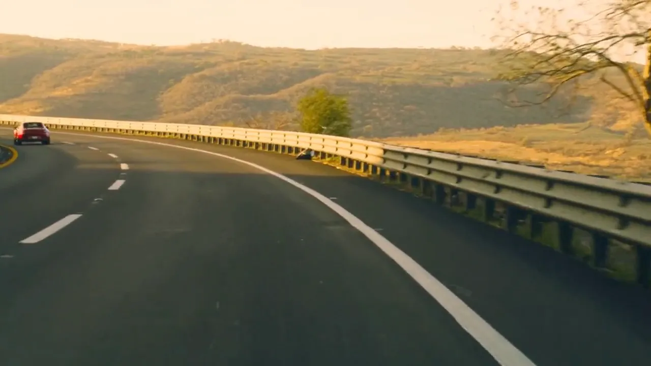 Un'auto rossa percorre una strada in curva all'alba